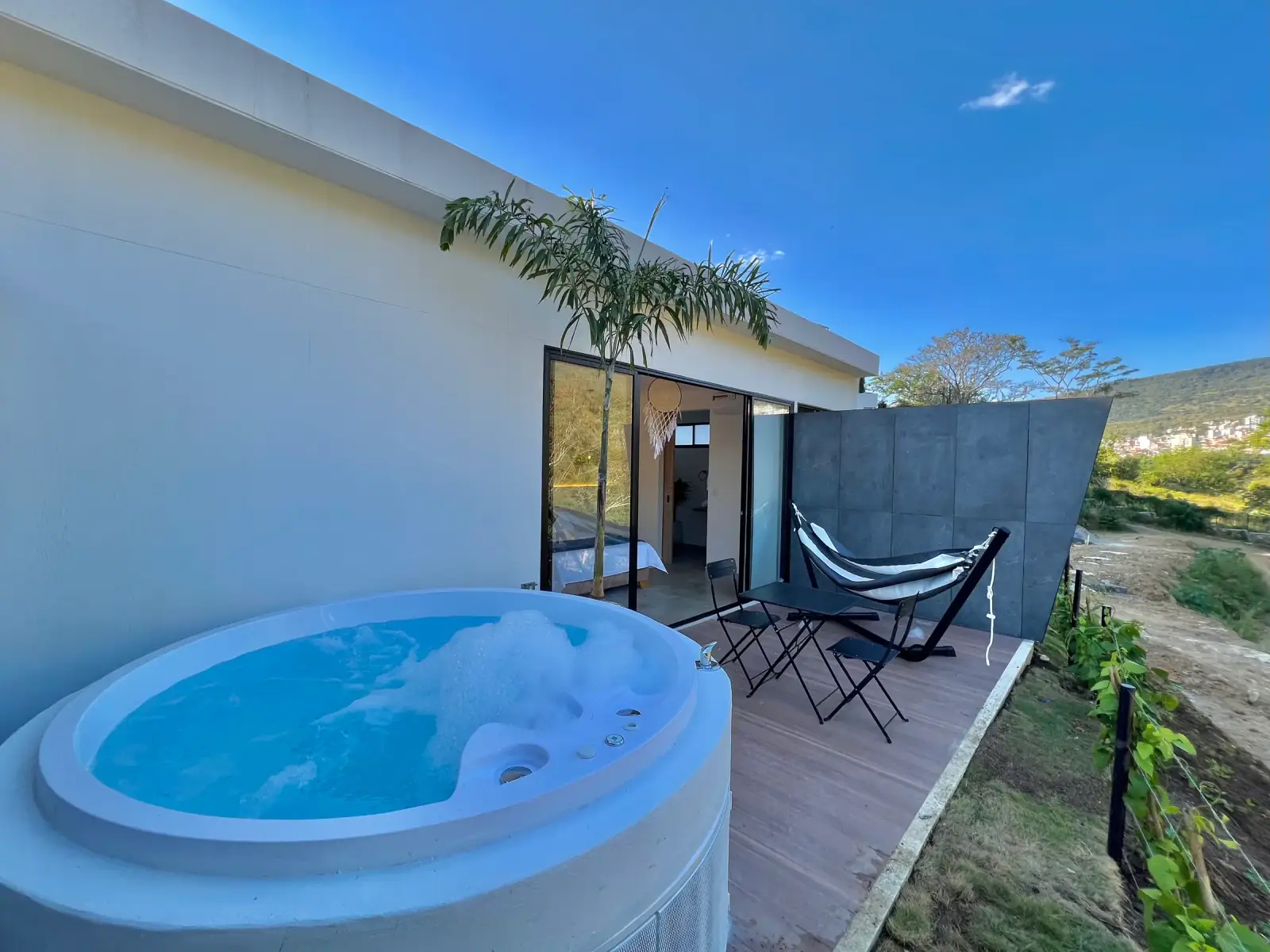 Burbujas en el jacuzzi del Glamping Deluxe; al fondo, la hamaca negra, una palma y el ventanal de la cabaña