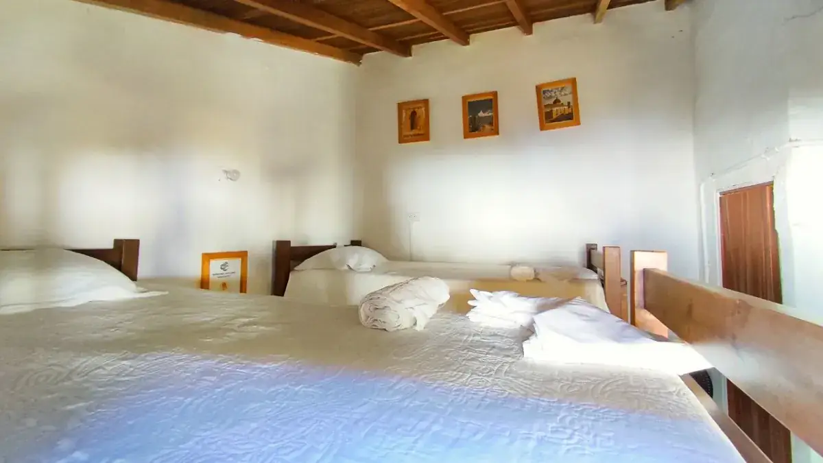 Habitación Familiar de paredes blancas, ropa de cama blanca, tres cuadros pequeños y techo de madera